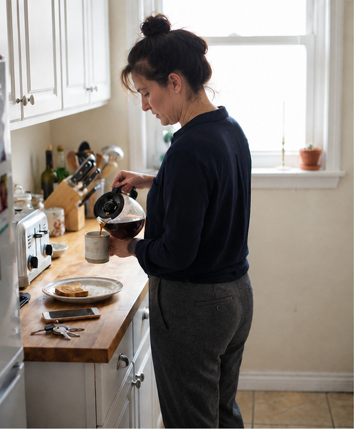 Mujer sirviéndose café en la cocina por la mañana, vestida para salir
